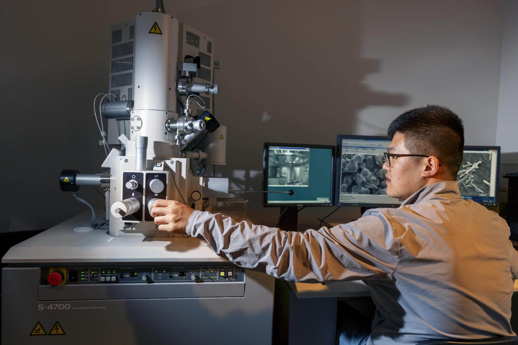 A man adjusts dials on an electron microscope.